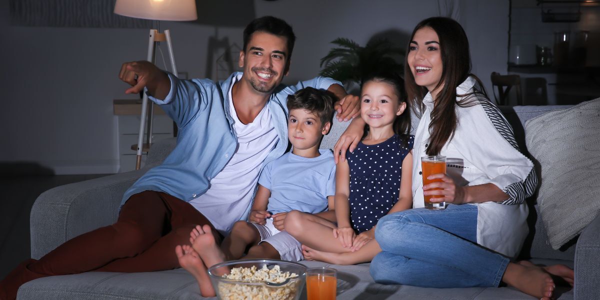 A happy family watches TV together on the sofa