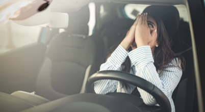 A woman in a car looks concerned by a noise from the car roof