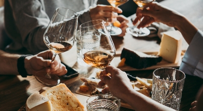 Close up of hands raising glasses of rosé wine in a toast