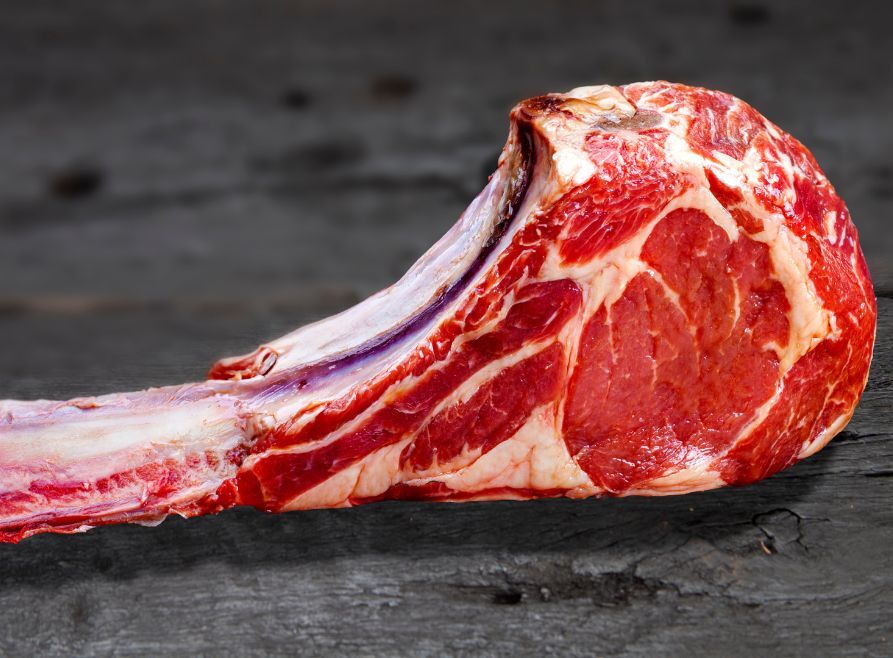A tomahawk steak with white marbled fat.